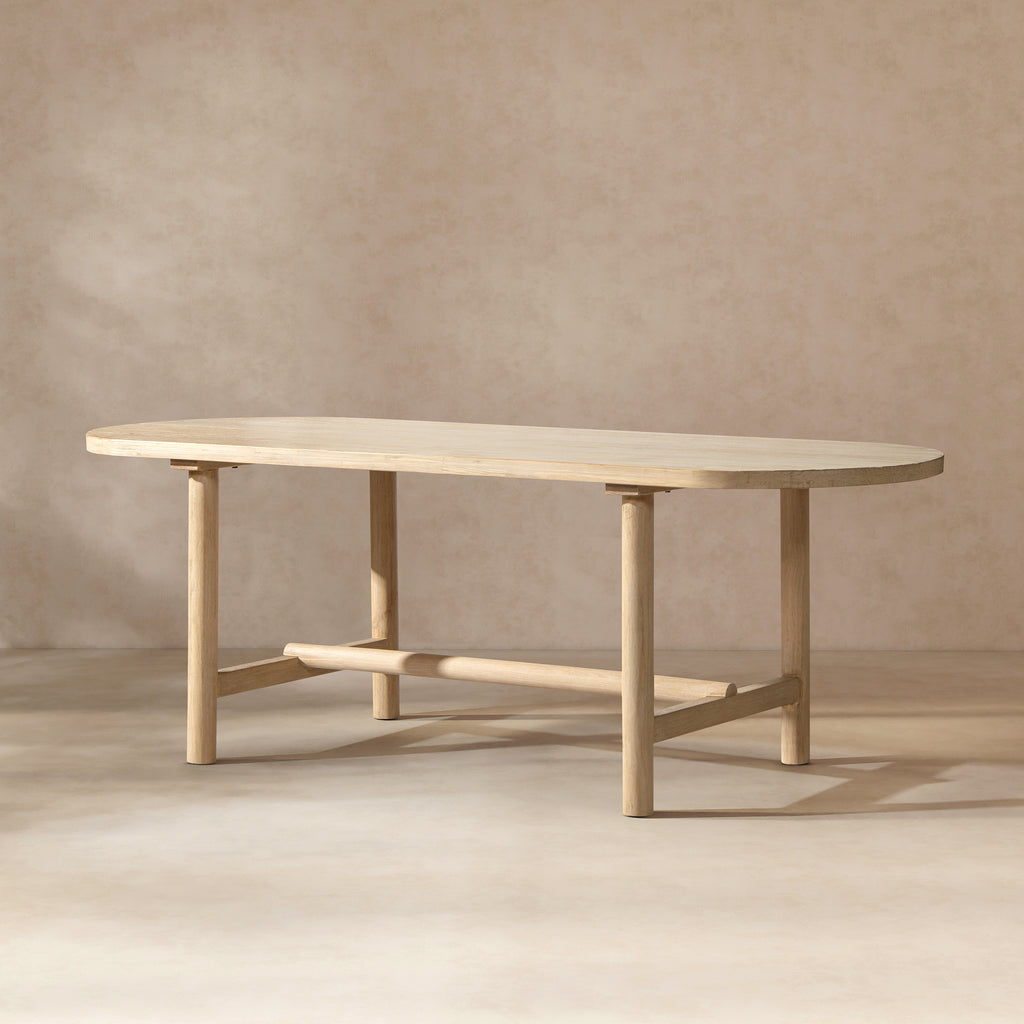 Oval dining table in light natural cerused reclaimed pine with four cylindrical legs and a central support beam.
