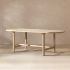 Oval dining table in light natural cerused reclaimed pine with four cylindrical legs and a central support beam.