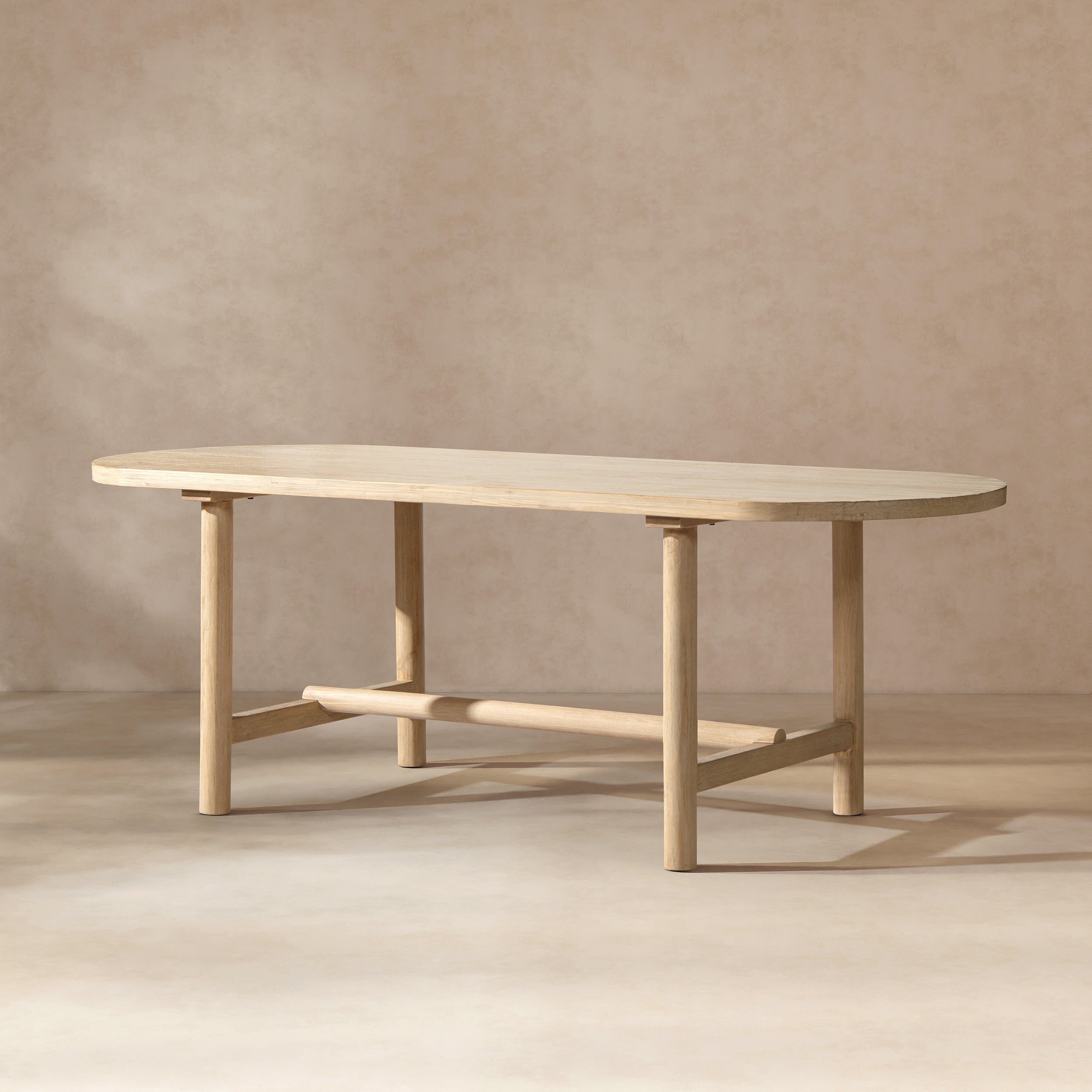 Oval dining table in light natural cerused reclaimed pine with four cylindrical legs and a central support beam.