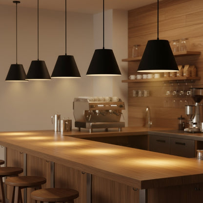 Five 16 inch LED black pendant lights suspended above a wooden bar. Sleek and modern lighting for commercial or home use.