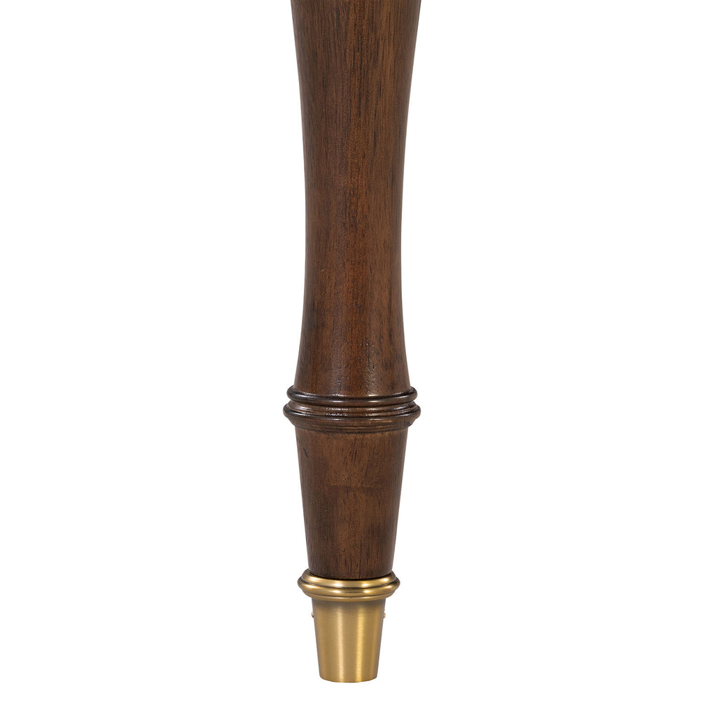 Close-up of solid wood dining chair leg with elegant gold-capped foot, showcasing craftsmanship and transitional design detail.