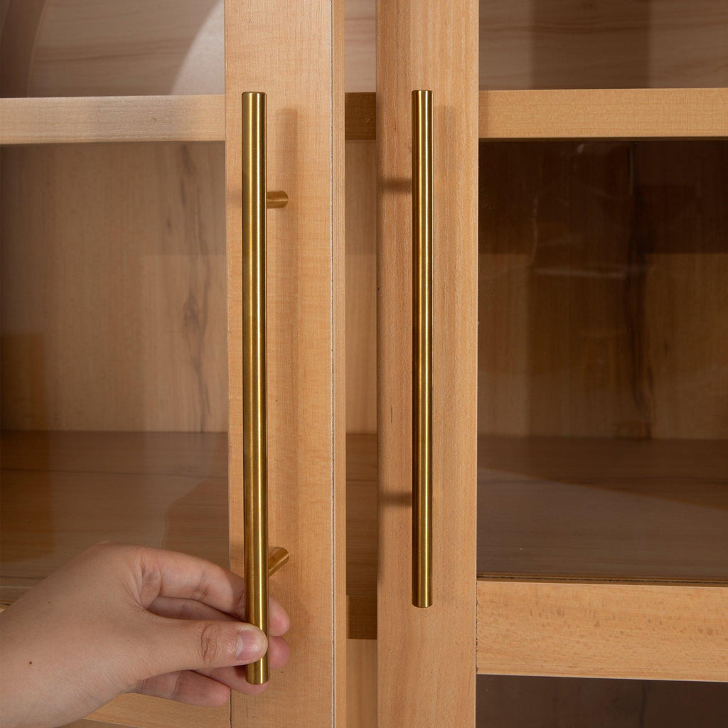 Hand opening gold handle on arched kitchen pantry cabinet, demonstrating ease of access to interior storage.