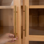 Hand opening gold handle on arched kitchen pantry cabinet, demonstrating ease of access to interior storage.