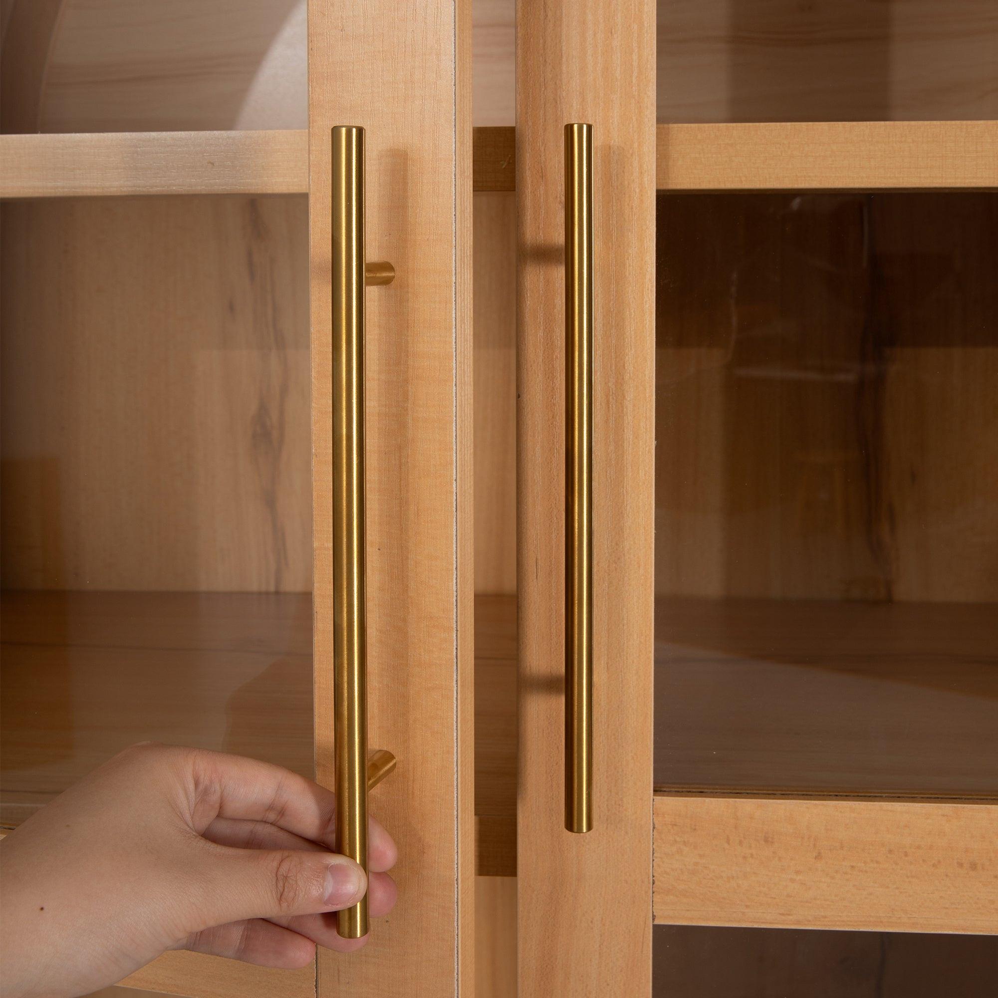 Hand opening gold handle on arched kitchen pantry cabinet, demonstrating ease of access to interior storage.