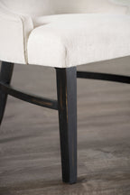 Close-up of black wooden legs and beige padded seat of transitional dining arm chair, showcasing quality craftsmanship.