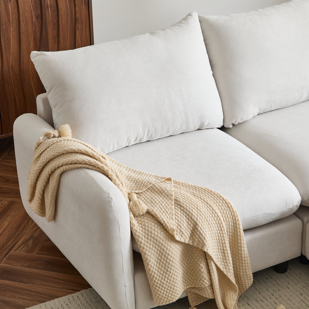 Close-up of left armrest and cushion of the 99 in. L shaped modular sectional sofa, showcasing soft white upholstery and beige throw.