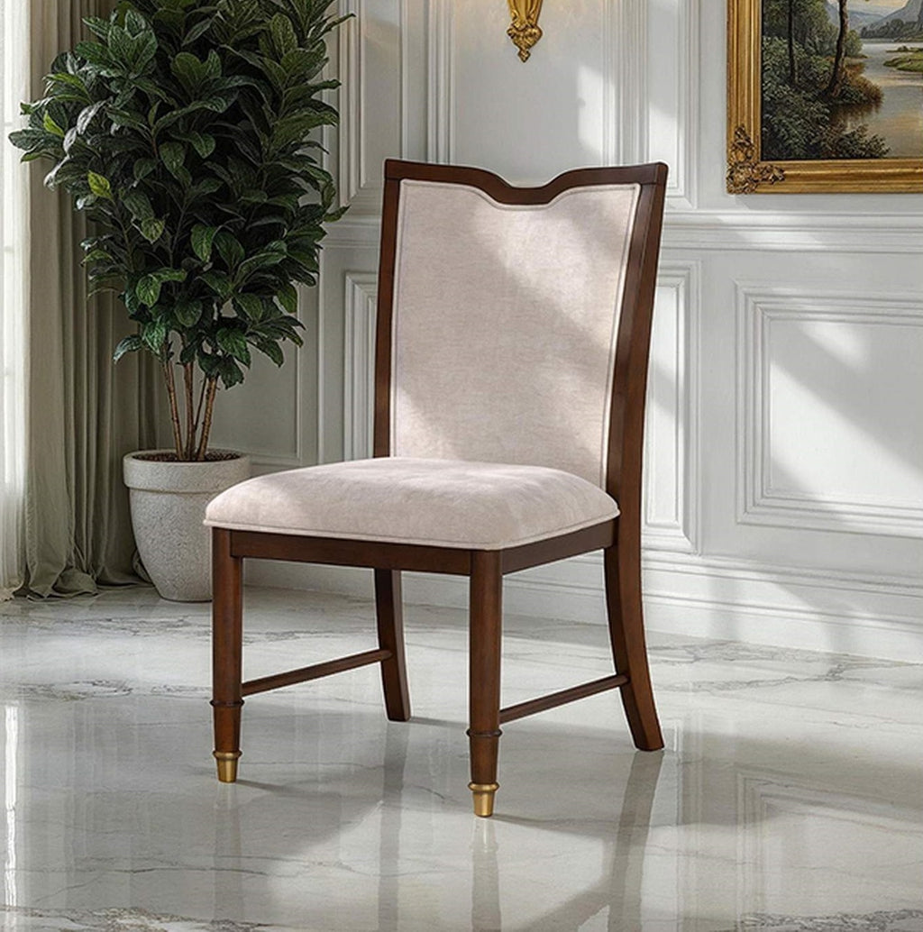 Transitional dining chair with upholstered seat and backrest, solid wood frame, and gold-capped legs in a classic interior setting.