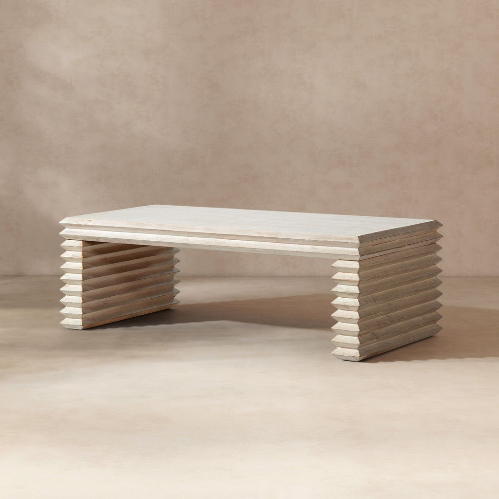 Whitewashed reclaimed pine coffee table featuring a geometric, stacked-wood waterfall base in a natural finish.