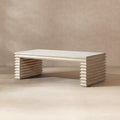 Whitewashed reclaimed pine coffee table featuring a geometric, stacked-wood waterfall base in a natural finish.