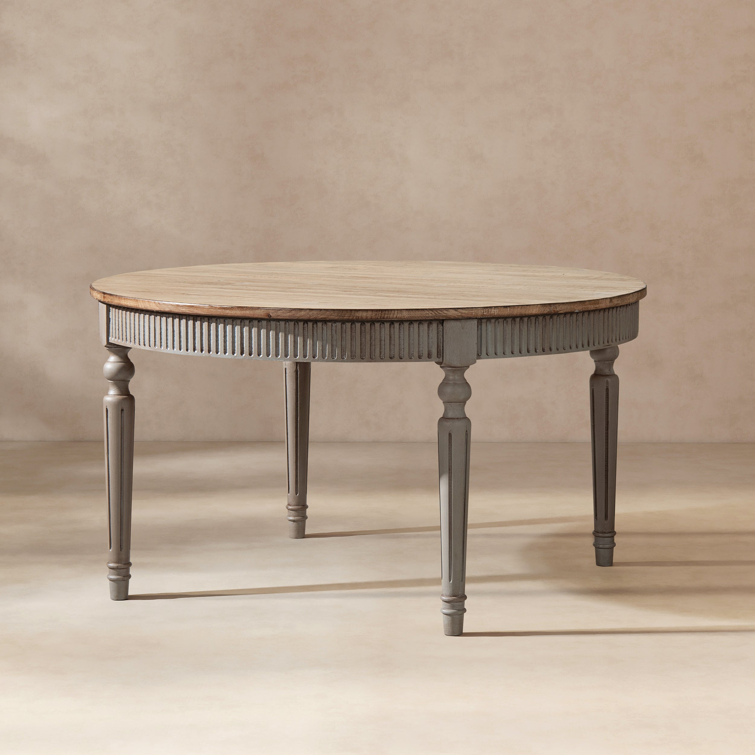 Round reclaimed pine dining table with a natural wood top and fluted antique blue-grey apron and tapered legs.