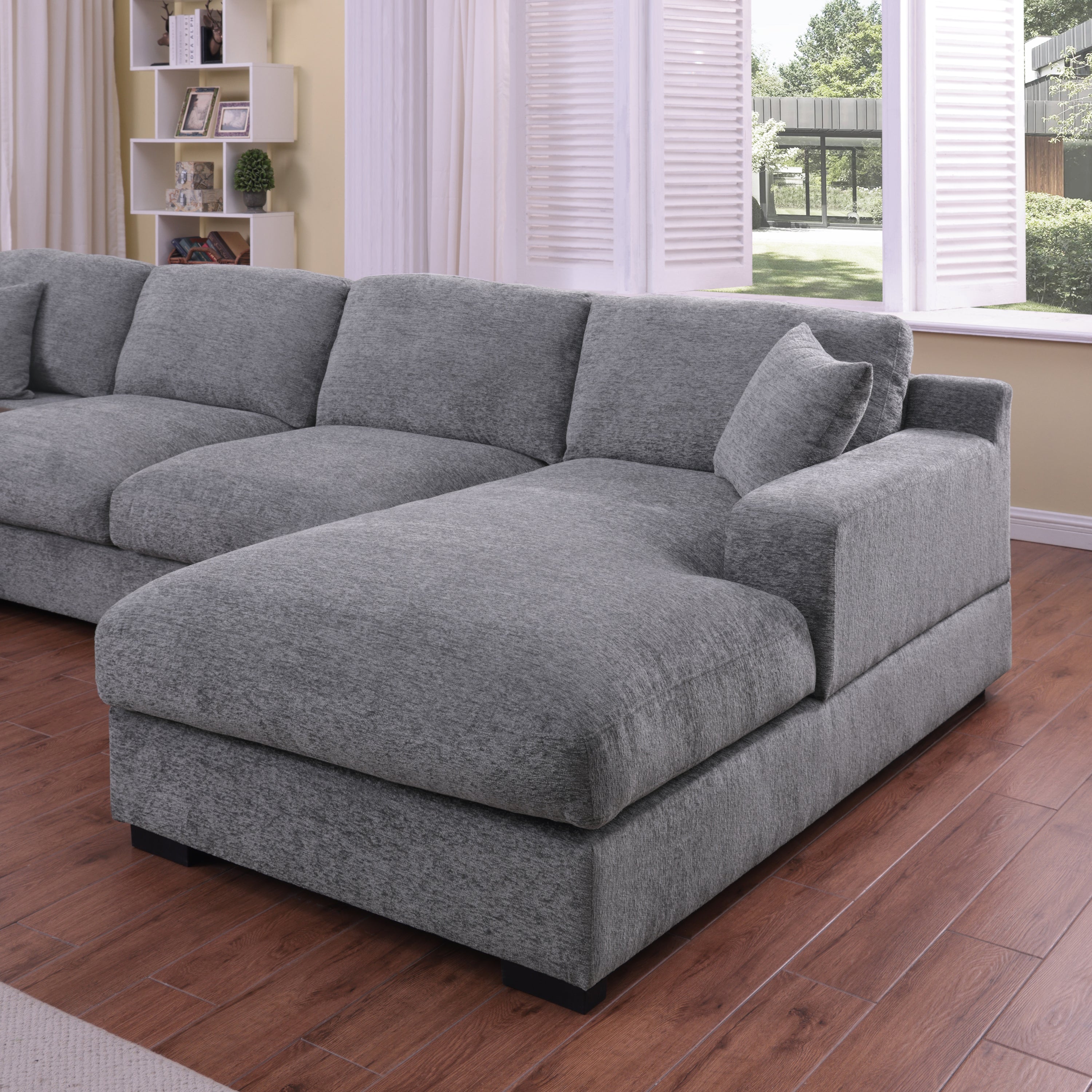 Right-facing chaise of light gray chenille sectional sofa with plush cushioning. Ideal for lounging in a modern living space.