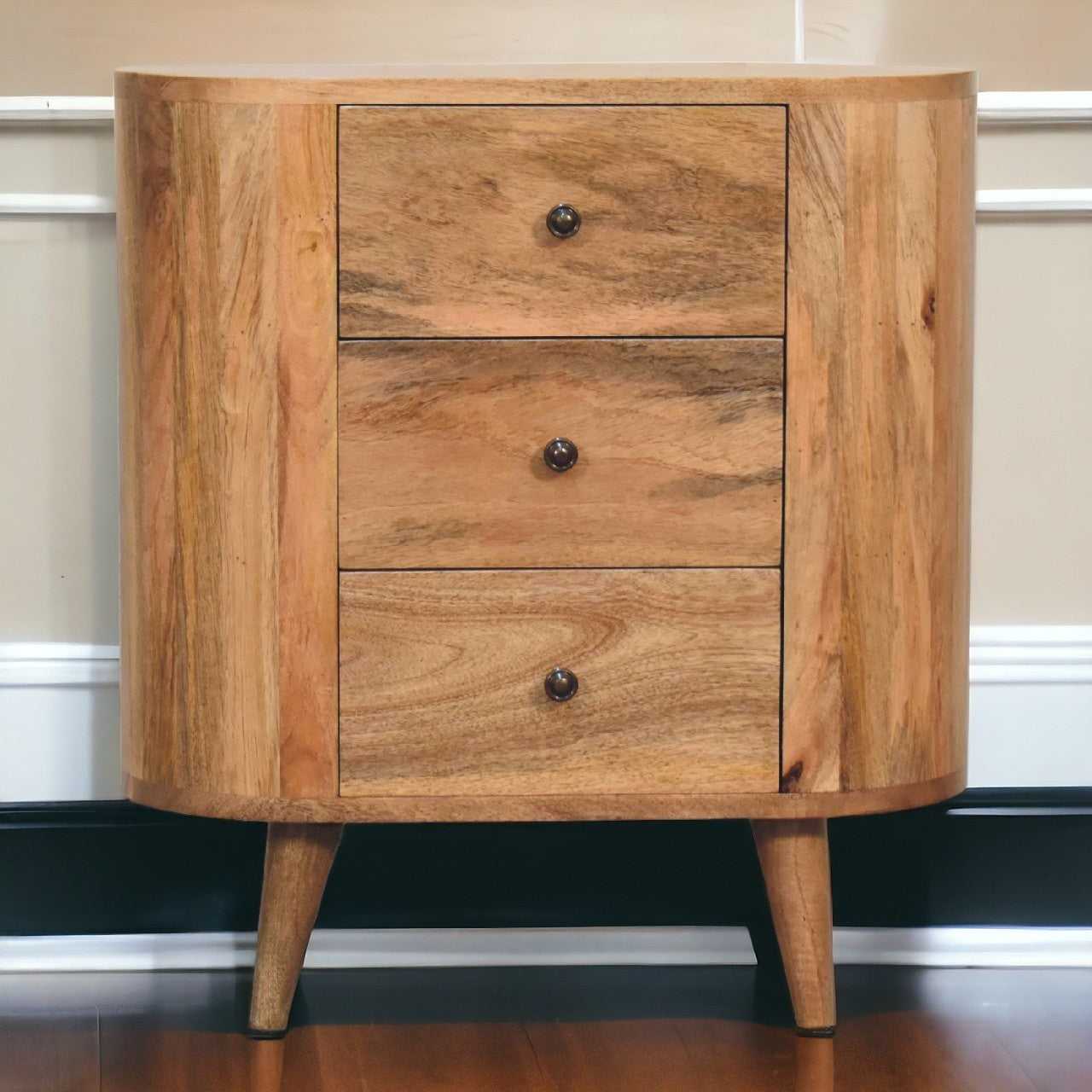 Wooden cabinet with three drawers against a neutral wall.