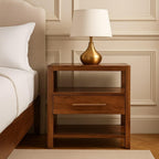 Wooden nightstand with a gold lamp against a beige wall.
