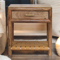 Wooden side table with a drawer and woven shelf in a home setting