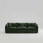 Green sofa in a living room with large windows and neutral decor