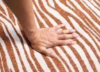 Hand on a textured surface with orange and white stripes