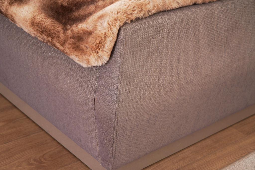 Corner detail of Lorenzo Queen Bed footboard in gray fabric with smooth curves and modern wooden base.