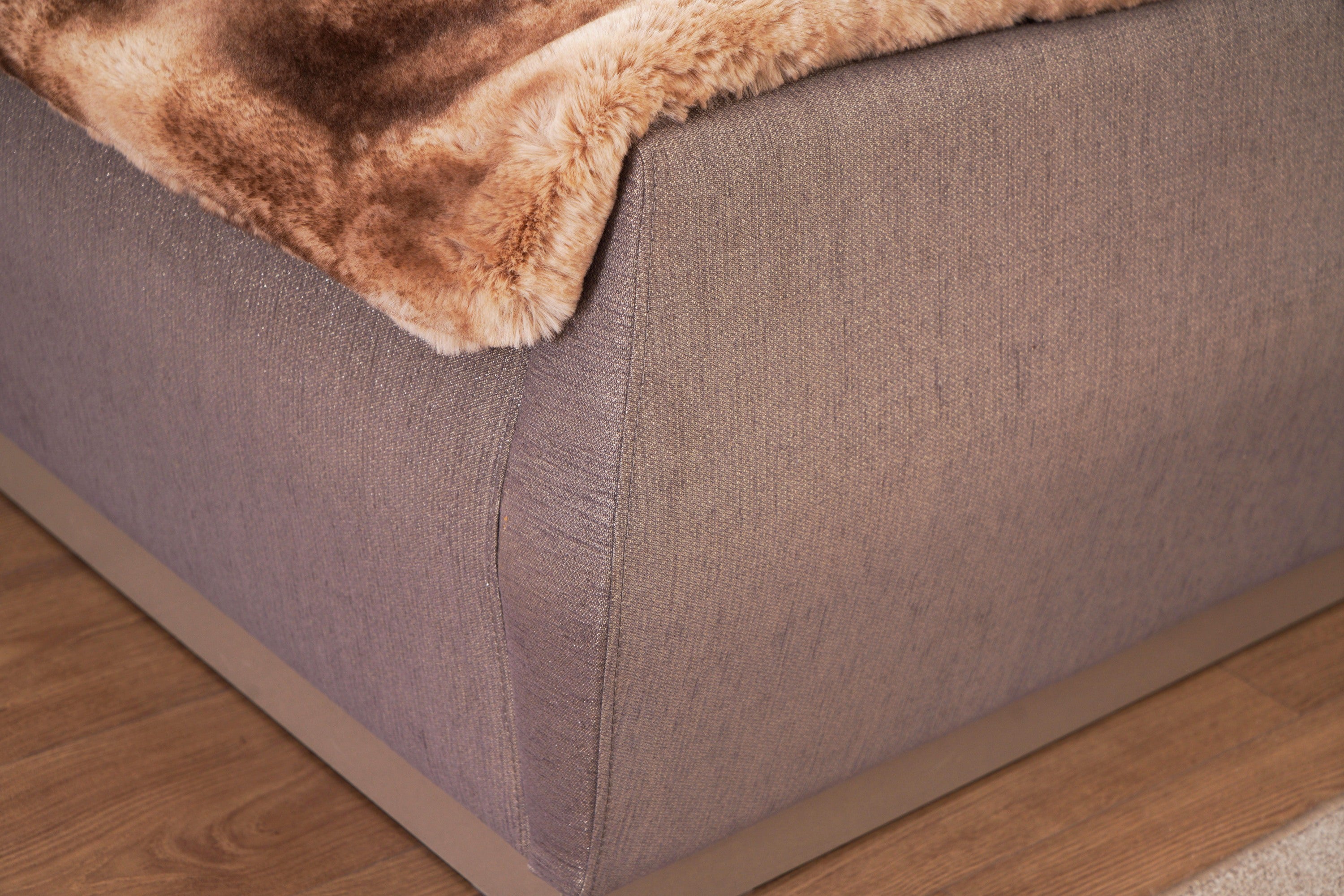 Corner detail of Lorenzo Queen Bed footboard in gray fabric with smooth curves and modern wooden base.