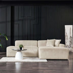 Cream corduroy right-facing sectional sofa with a modern, low-profile design set against a black paneled wall.