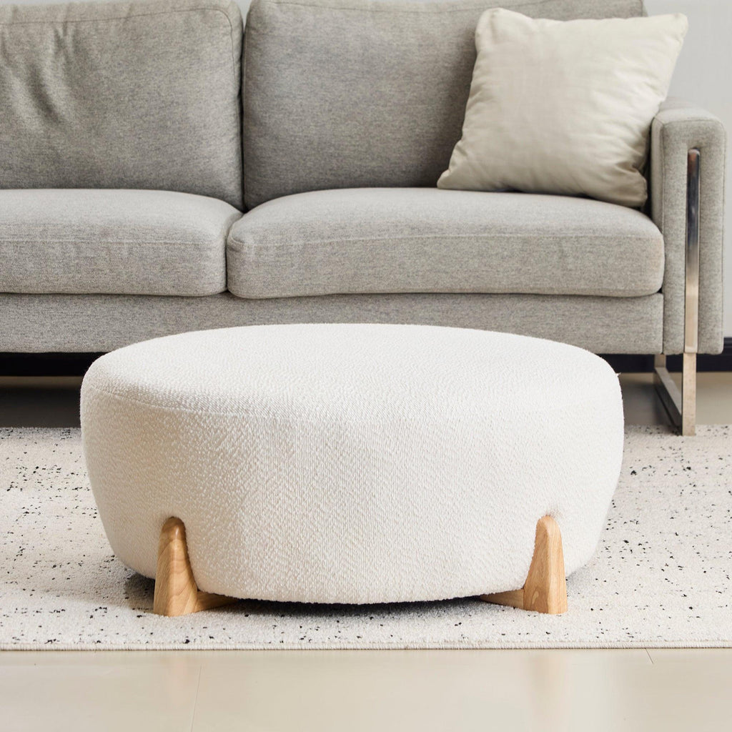 Modish Round Ottoman with Boucle Top and Natural Wood Legs.