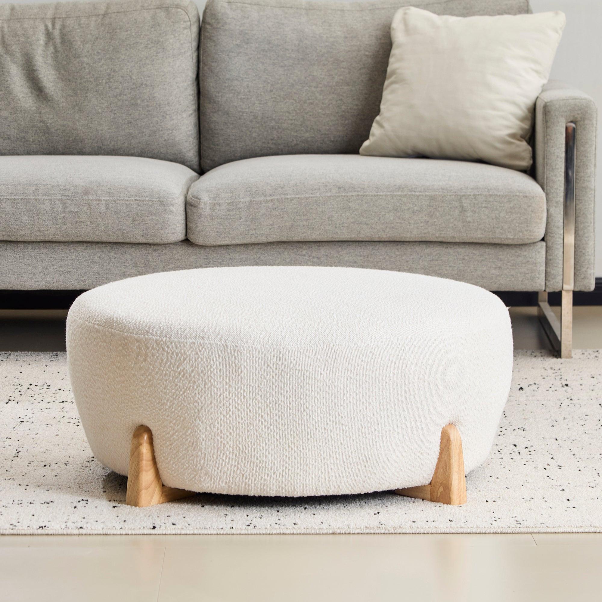 Modish Round Ottoman with Boucle Top and Natural Wood Legs.