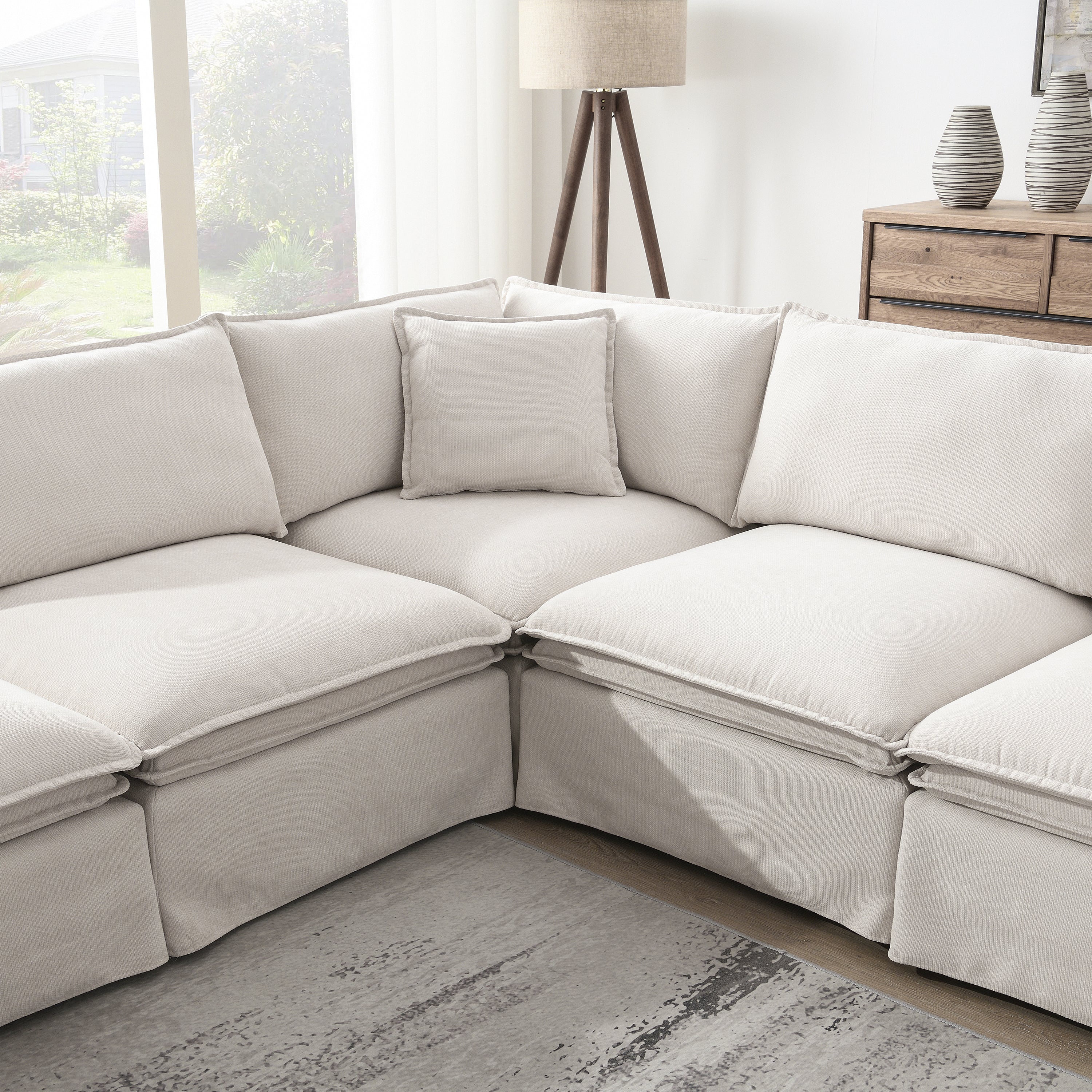 Corner section of modular sectional sofa with ottoman, showing plush back cushions and soft fabric ideal for cozy living room lounging.