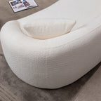 Detail of the armrest and cushion on minimalist white curved sofa, emphasizing its rounded modern design.