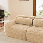 Left corner of light khaki modular plush sofa in a modern living room, featuring soft cushions and plush upholstery.