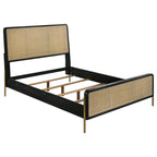 Black queen bed frame with natural woven rattan panels, rounded corners, and slim metallic gold legs on a white background.