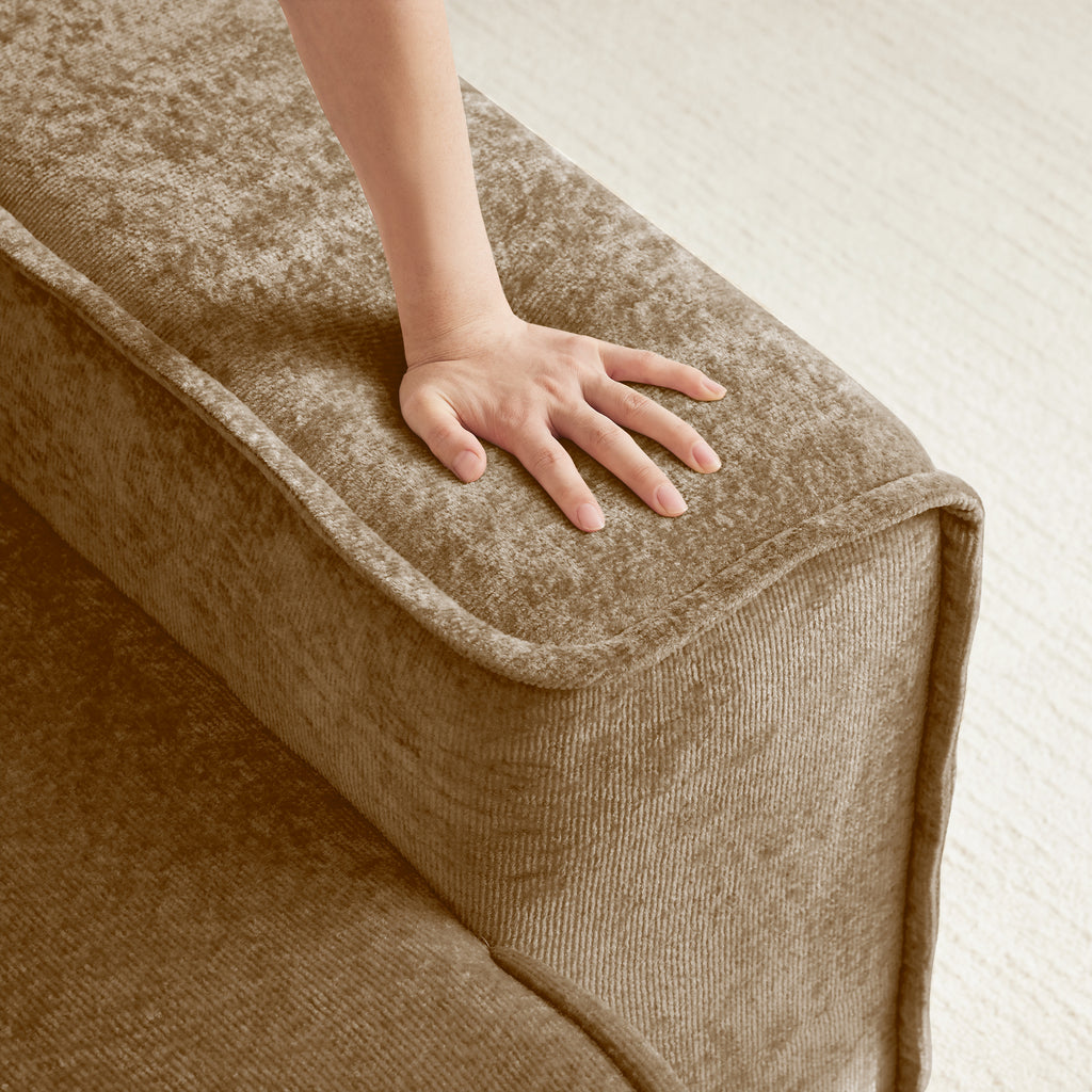 Hand pressing into cushion of Velvet Modular Sectional Sofa. Demonstrates cloud-like comfort and high-density foam support.