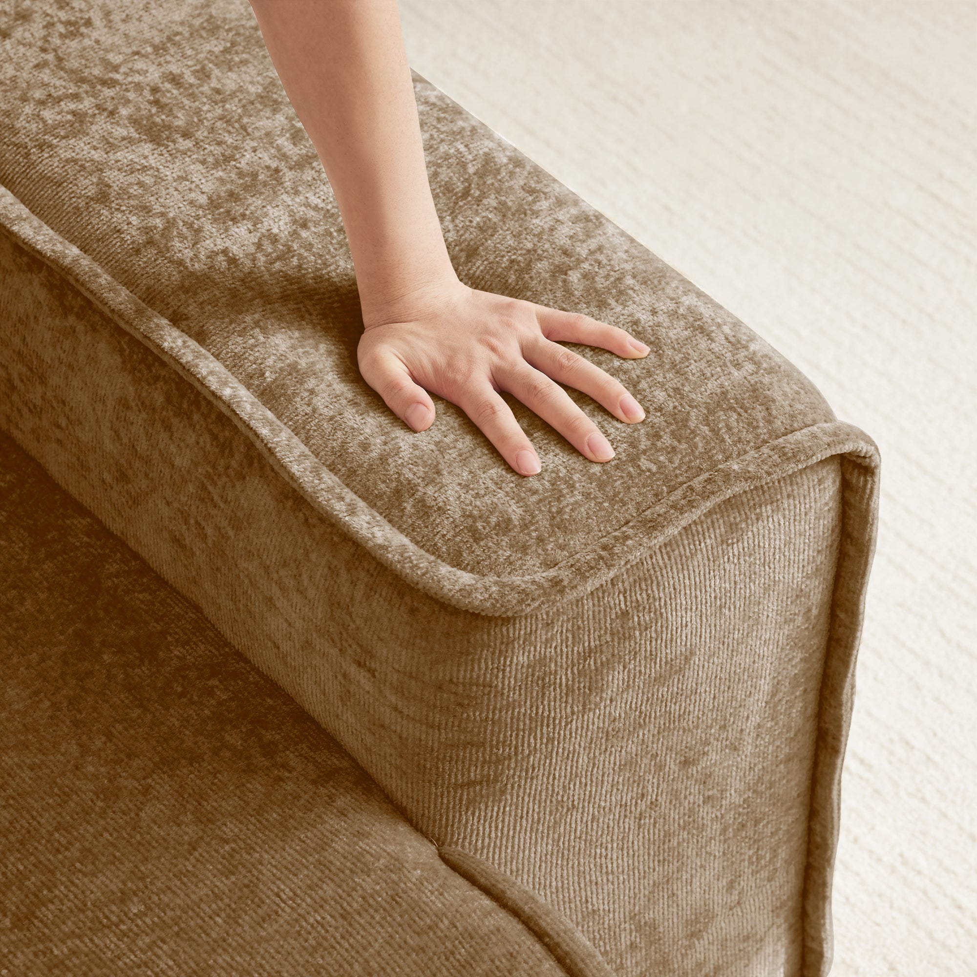 Hand pressing into cushion of Velvet Modular Sectional Sofa. Demonstrates cloud-like comfort and high-density foam support.