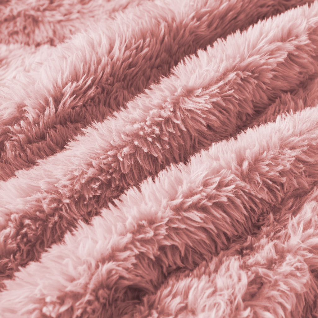 Close-up of soft plush fabric texture on pink modular sofa chaise, highlighting cozy and luxurious material quality.