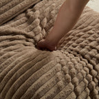 Close-up of hand pressing into soft corduroy cushion, highlighting the plush and comfortable texture of the chair.