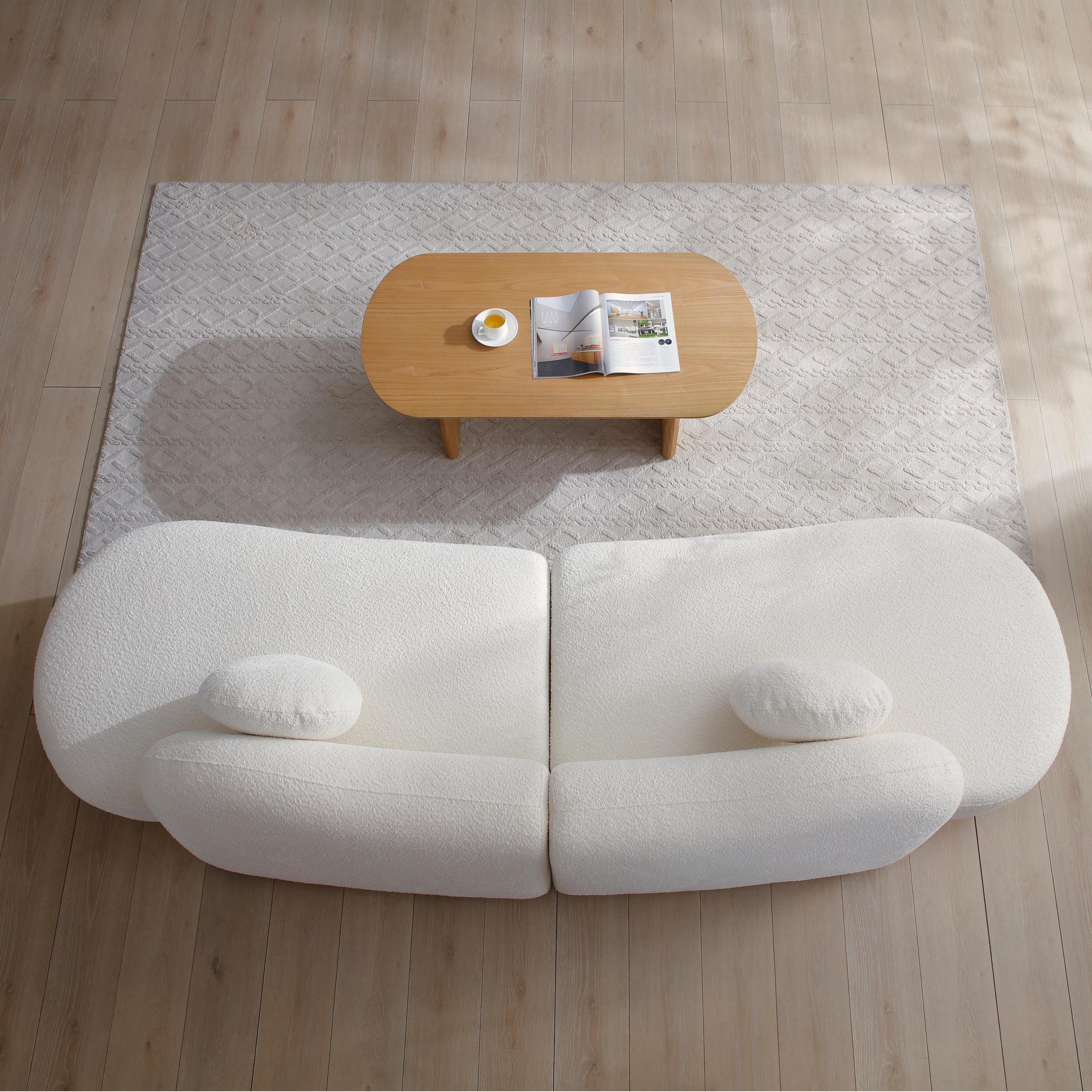 Overhead view of modern curved sofa on a neutral rug, emphasizing its modular layout and soft boucle fabric for cozy living spaces.