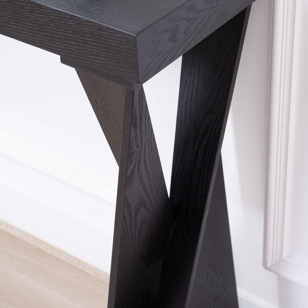 Detail of the crossed leg design on black console table, showcasing the sturdy and stylish construction.