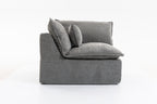 Side profile of the oversized modular sectional couch showing thick cushions and supportive armrest in grey velvet.