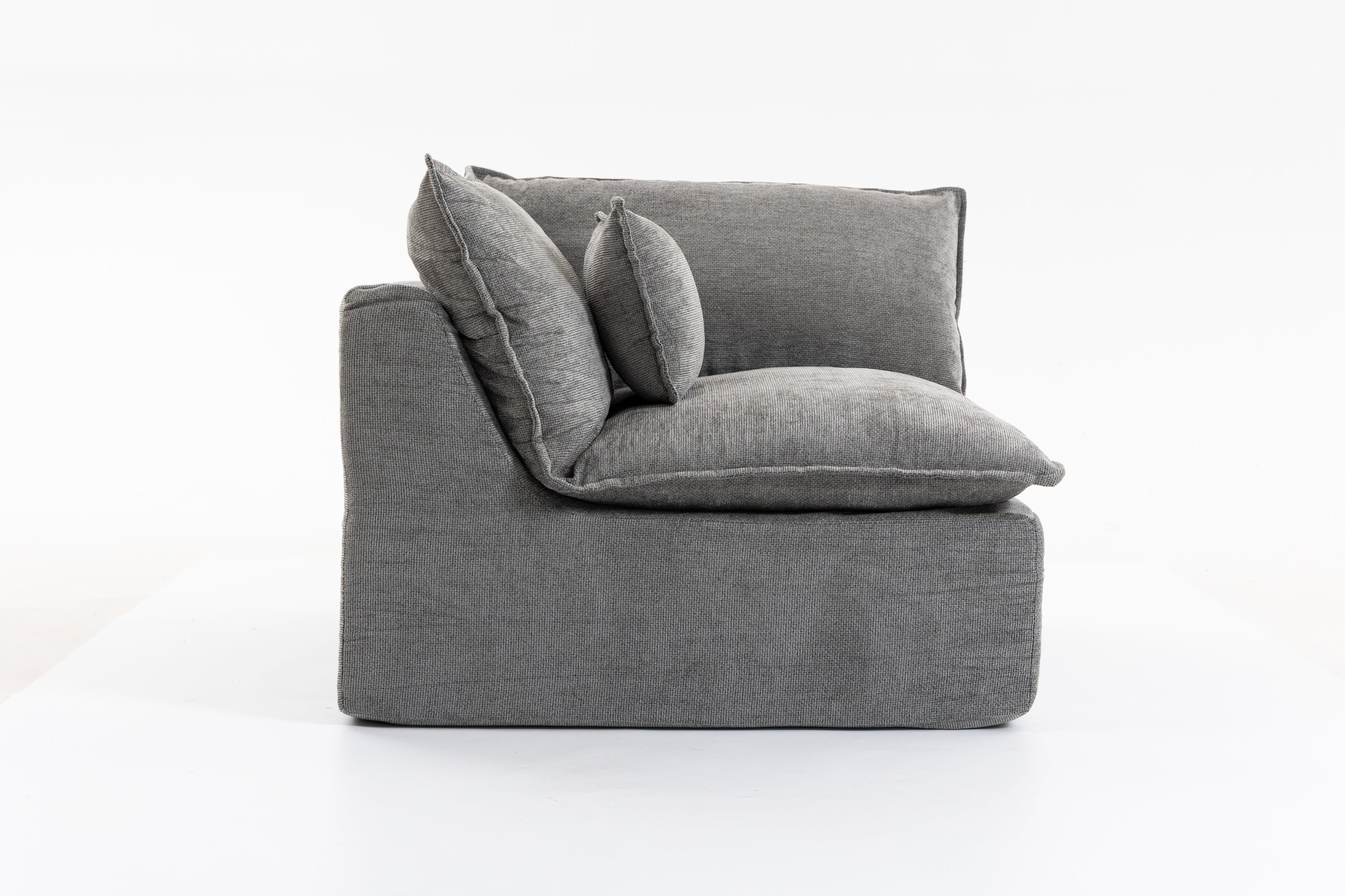 Side profile of the oversized modular sectional couch showing thick cushions and supportive armrest in grey velvet.