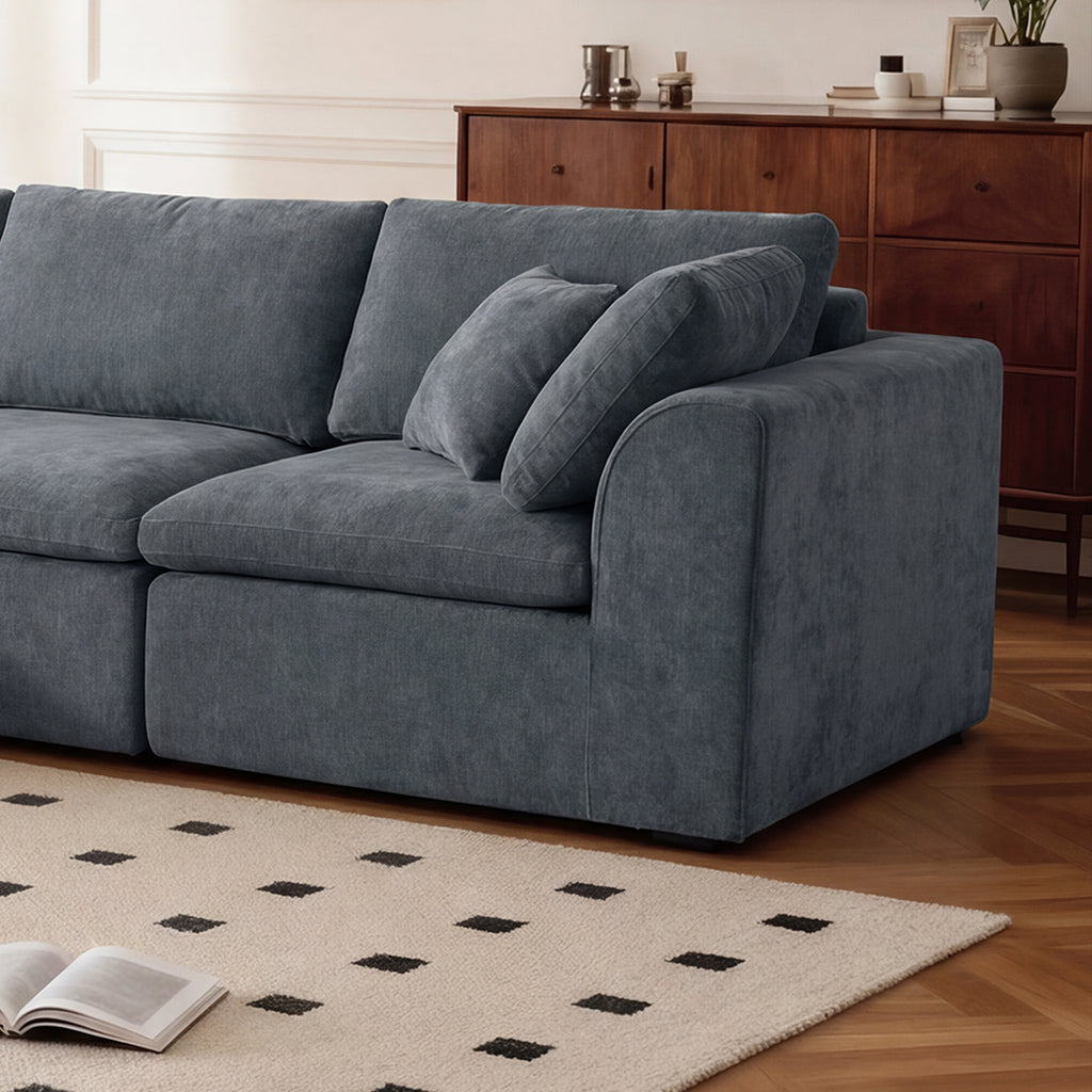 Close-up of right armrest and cushions on modern L-shaped sectional sofa with chaise, showcasing plush chenille texture.