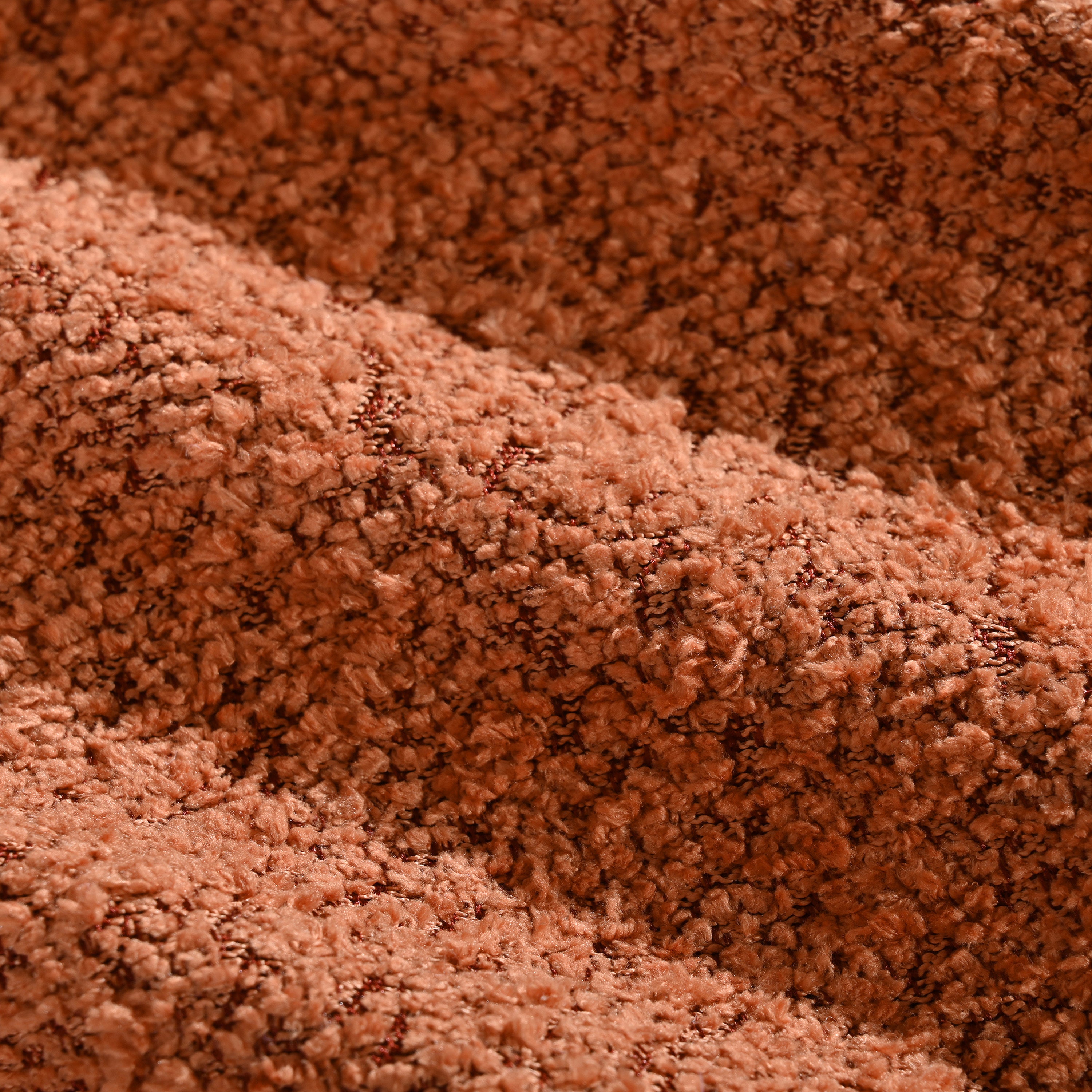 Close-up of rust-colored boucle fabric texture used on the modular sectional sofa, emphasizing its soft, cozy, and durable upholstery material.