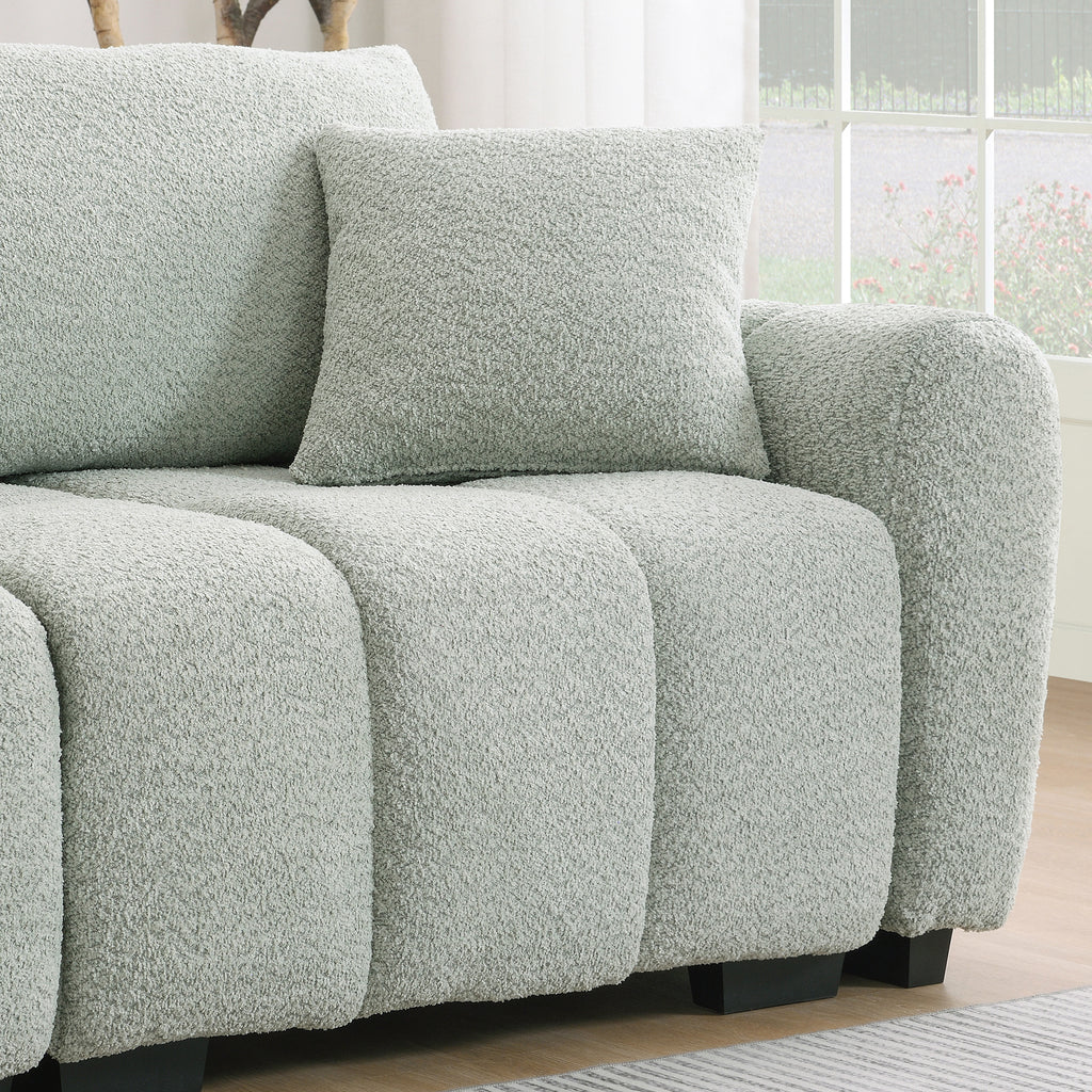Armrest and cushion detail of modular sectional sofa with ottoman, showcasing thick padding and soft boucle upholstery.