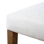 Corner close-up of rustic dining chair seat with textured white upholstery and solid wood leg, part of a 2pc set.