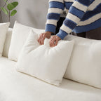 Person fluffing a back cushion on the oversized L-shape sectional sofa, demonstrating the sofa's plush and supportive comfort.