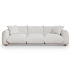 Modern 100-inch cream boucle sofa with deep cushions, two matching throw pillows, and low-profile solid wood legs.