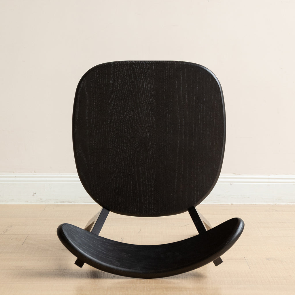 Bottom view of black wood dining chair seat, displaying the solid oak grain and craftsmanship.