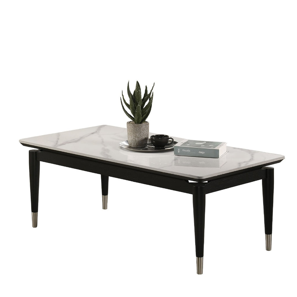 Black and white contemporary coffee table with sintered stone top and metal-capped legs, shown with books and a plant for modern decor.