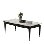 Black and white contemporary coffee table with sintered stone top and metal-capped legs, shown with books and a plant for modern decor.