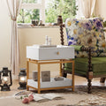 Modern white end table with a gold metal frame, featuring a single storage drawer and an open bottom display shelf.