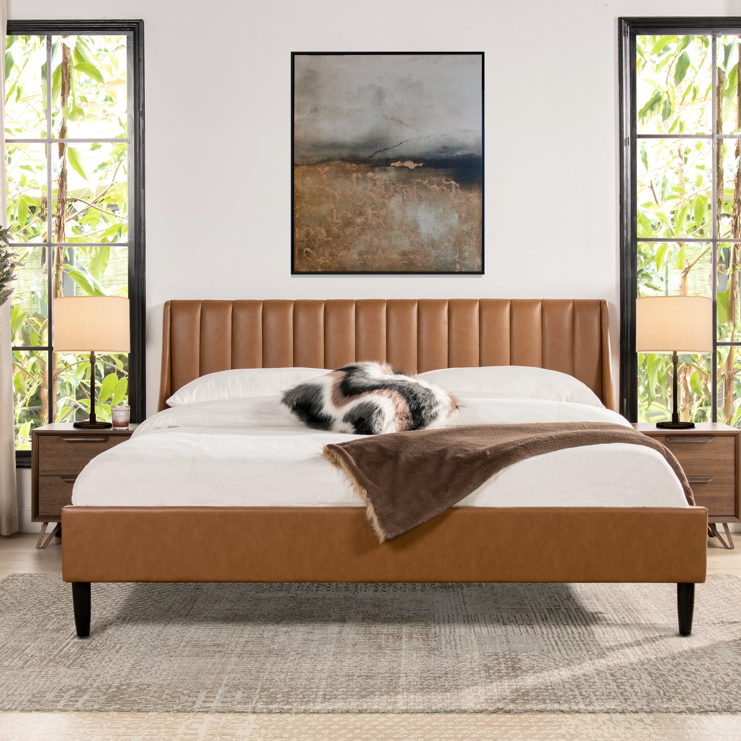 King faux leather platform bed with vertical tufted headboard in caramel tan brown, styled in a modern bedroom with natural light.