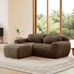 Angled view of L-shaped modular sofa in plush chocolate fabric, featuring ergonomic contours and a matching ottoman.