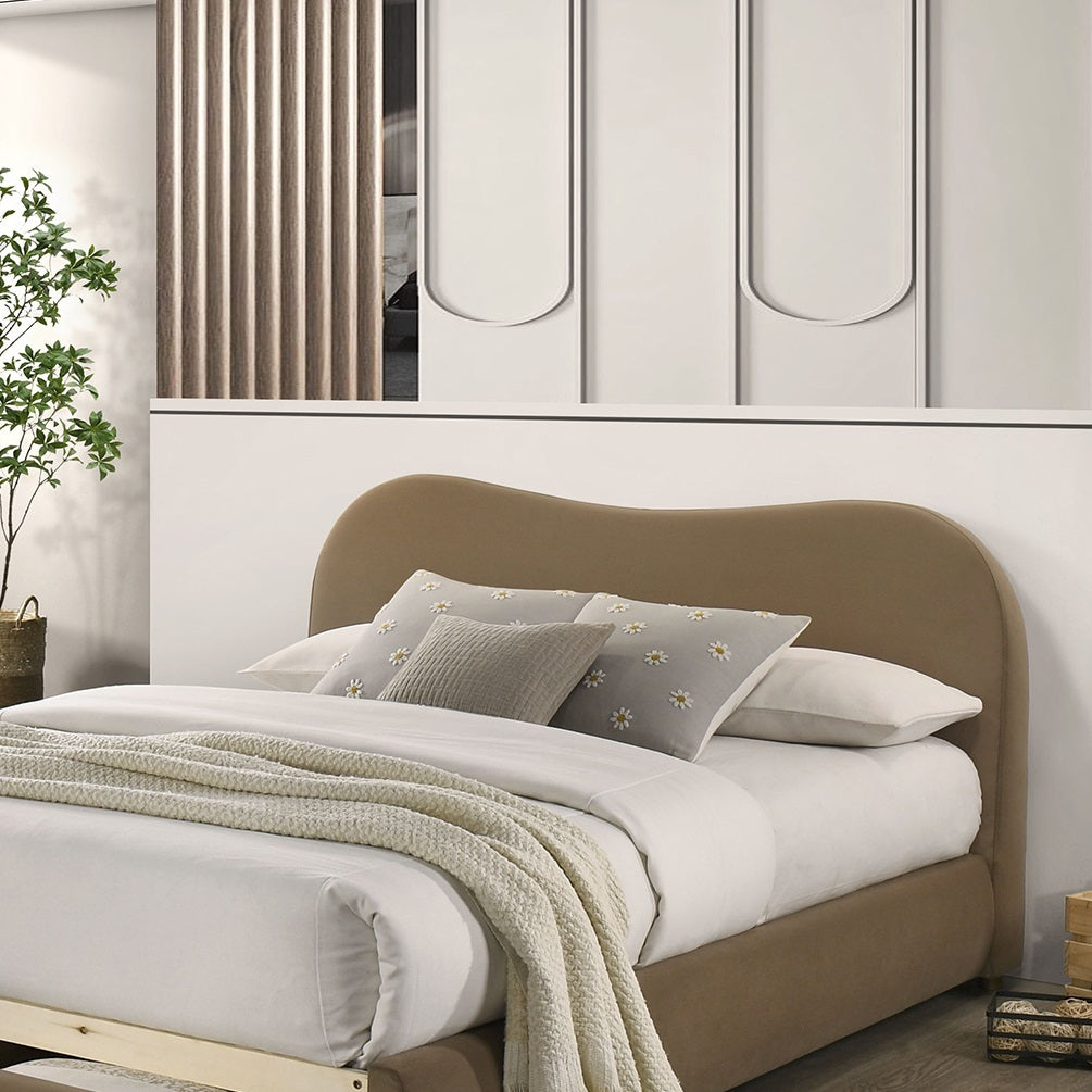 Close-up of queen bed frame with curved velvet headboard and layered bedding. Upholstered wood frame adds elegance to bedroom interiors.